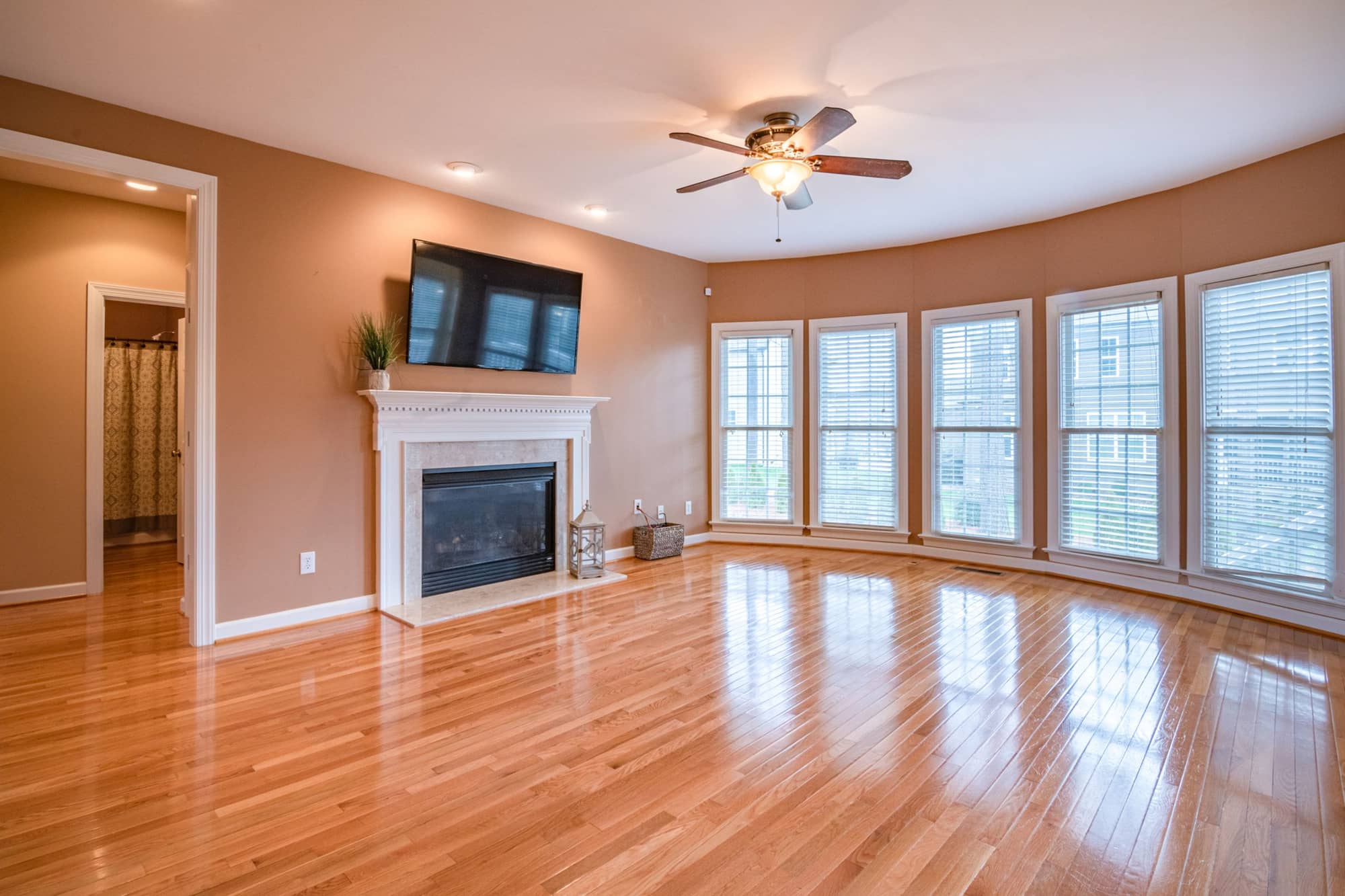 Empty living room with wooden flooring, a fireplace and large windows
