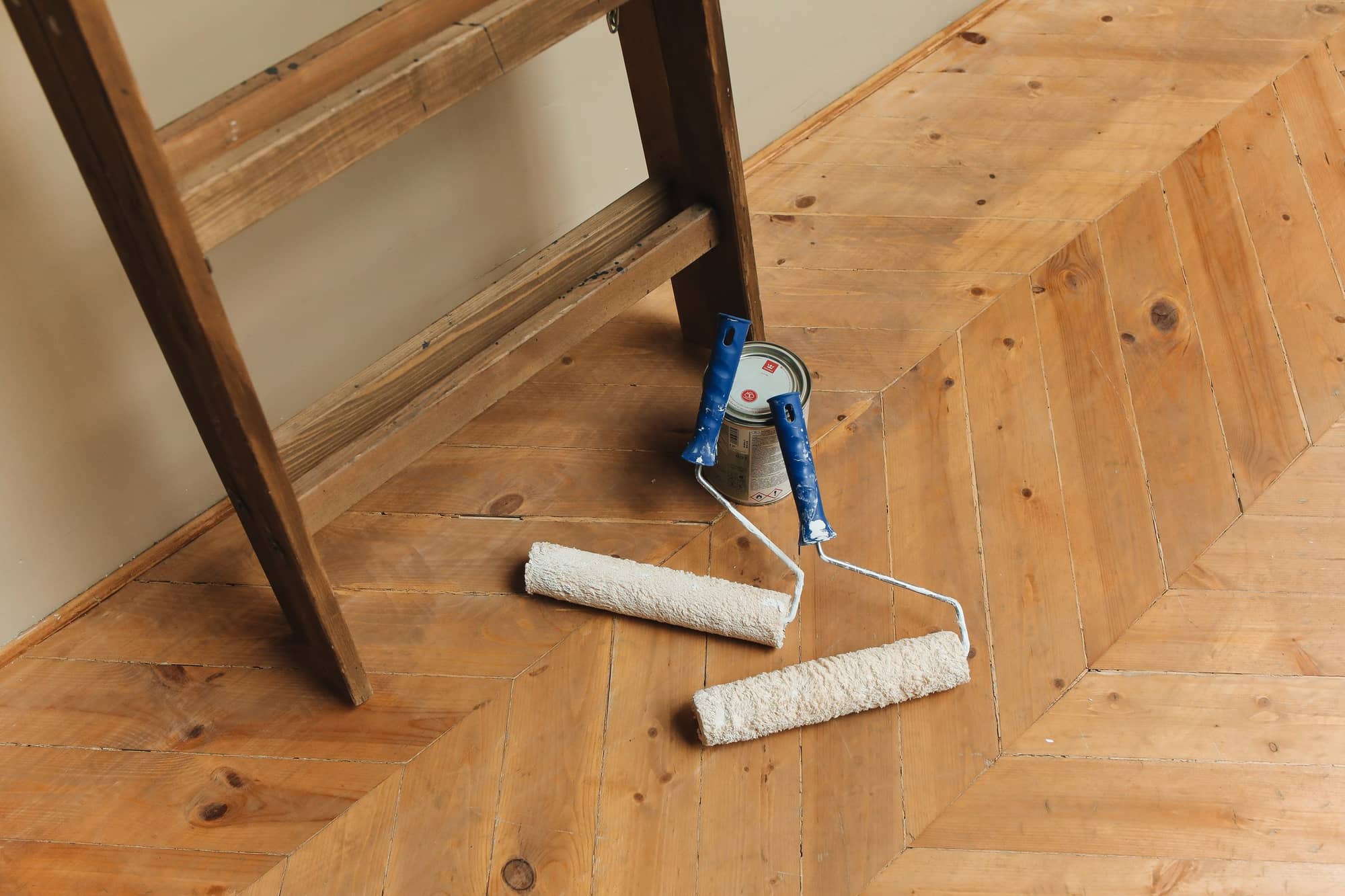 Roller and paint tray on a wooden floor beside a doorway